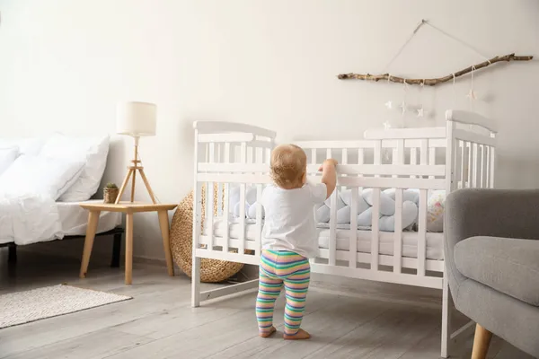 可爱的小宝宝站在家里的婴儿床旁边 — 图库照片