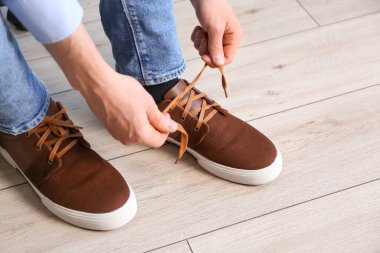 Ayakkabı bağcıklarını evde bağlayan adam, yakın plan.