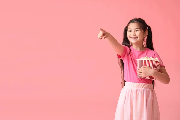 Aranyos Lány Vödör Popcorn Mutat Valamit Rózsaszín Háttér — Stock Fotó