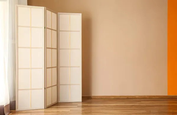 Modern folding screen near beige wall