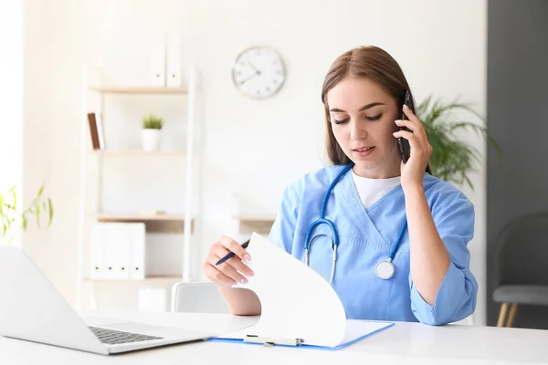 Vrouwelijke Arts Gesprek Met Mobiele Telefoon Aan Tafel Kliniek — Stockfoto