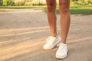 Parkta beyaz spor ayakkabı giyen kadın bacakları