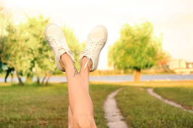 Parkta beyaz spor ayakkabı giyen kadın bacakları