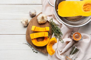 Beyaz ahşap arka planda taze balkabağı parçaları olan tahta.