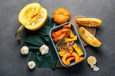 Fırında kabak parçaları ve siyah arka planda taze sebzelerle dolu bir tabak.