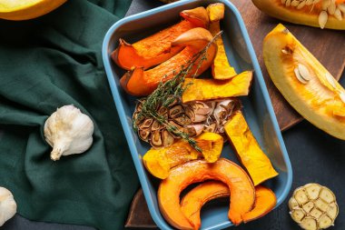 Siyah arkaplanda fırında kabak parçaları olan bir tabak.