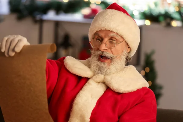 Удивленный Санта Клаус Читает Список Желаний Дома Канун Рождества — стоковое фото