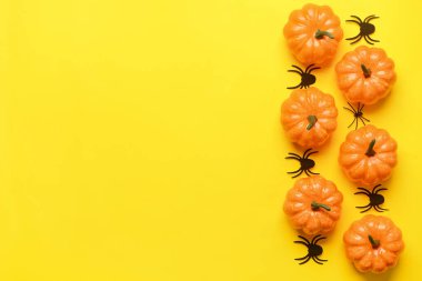 Sarı arka planda örümcekler olan Cadılar Bayramı balkabakları