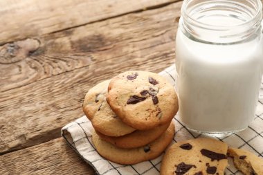 Çikolata parçalı nefis ev yapımı kurabiyeler ve ahşap arka planda bir kavanoz mason sütü, yakın plan.