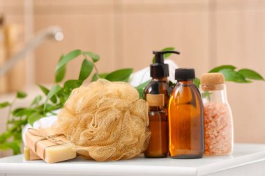 Sofrada sabun, banyo süngeri ve kozmetik ürünleri şişeleri var.