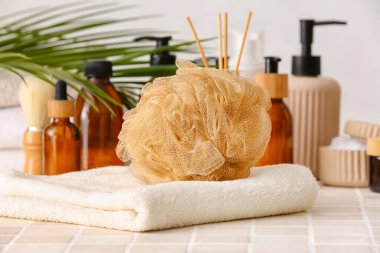 Havlu, sünger ve banyo malzemeleri fayans masasında.