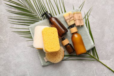 Süngerli banyo malzemeleri ve arka planda palmiye yaprağı.