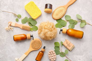 Süngerli banyo malzemeleri ve hafif arka planda bitki dalları.