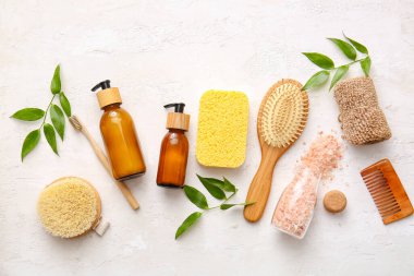 Süngerli banyo malzemeleri ve beyaz arka planda bitki dalları.