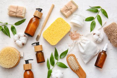Süngerli banyo malzemeleri ve beyaz arka planda bitki dalları.