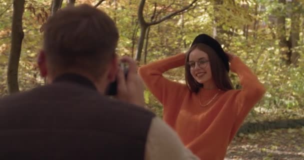 Молодой Человек Фотографирует Свою Девушку Осеннем Парке — стоковое видео