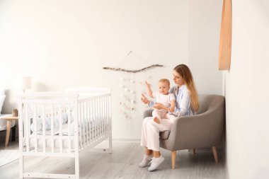 Genç anne ile evde koltukta oturan onun şirin bebek