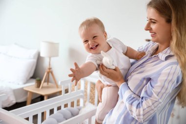 Genç anne oyuncak bebeğini kucağında tutuyor.