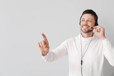 Kulaklıklı çağrı merkezinin gülümseyen danışmanı arka plandaki bir şeyi işaret ediyor.