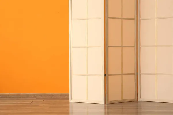 Modern folding screen near orange wall