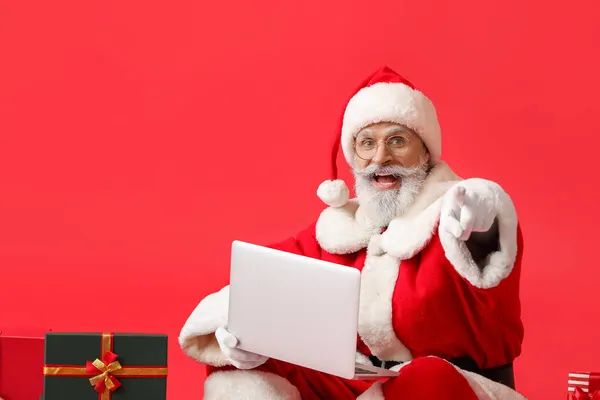 Weihnachtsmann Mit Laptop Zeigt Auf Betrachter Auf Farbigem Hintergrund — Stockfoto