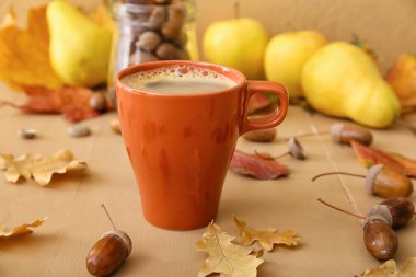 Bir fincan meşe palamudu ve sonbahar yapraklı kahve renkli ahşap masa, yakın plan.