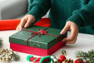 Kapalı bir masada Noel hediyesi kutulu bir kadın, yakın plan.