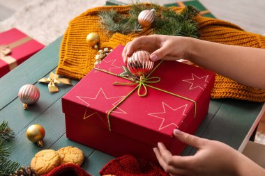 Odada Noel hediyesi kutusunu süsleyen kadın.