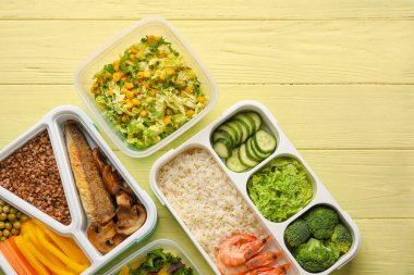 Renkli ahşap arka planda farklı sağlıklı yiyeceklere sahip kaplar, yakın plan.