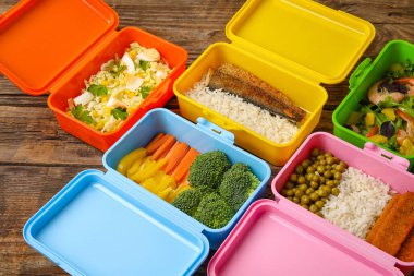 Tahta masada farklı sağlıklı yiyeceklerle dolu birçok plastik kap, yakın plan.