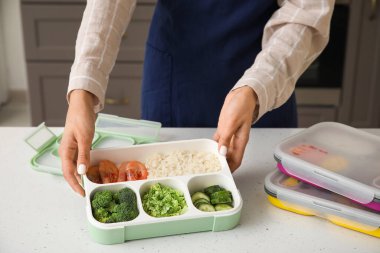 Kadın yemeklerini mutfaktaki konteynırlara dolduruyor.