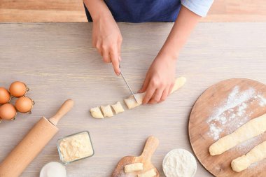 Genç bayan ahşap masada lezzetli hamur tatlısı pişiriyor.
