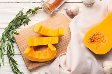 Beyaz ahşap arka planda taze balkabağı parçaları olan tahta.