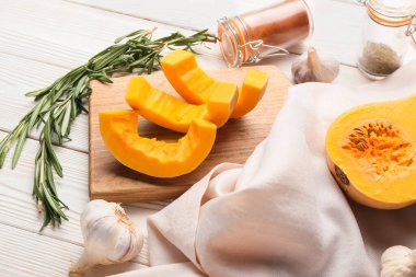 Beyaz ahşap arka planda taze balkabağı parçaları olan tahta.