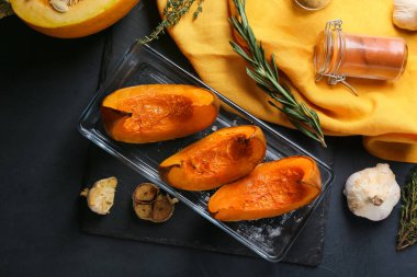 Siyah arkaplanda fırında kabak parçaları olan bir tabak.