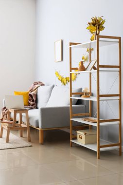 Raflar, rahat bir kanepe ve modern dizüstü bilgisayarlı ahşap bir masa.