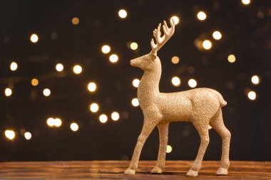 Koyu arkaplanda, ahşap masada altın ren geyiği.