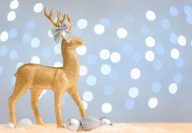 Altın ren geyiği ve Noel topları kar masasında arka planda