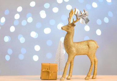 Altın ren geyiği ve Noel dekoru açık arkaplanda.