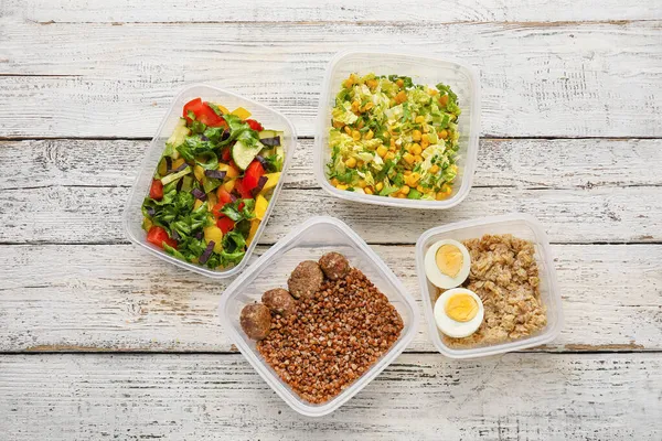 Hafif ahşap arka planda farklı lezzetli yemekleri olan kaplar.