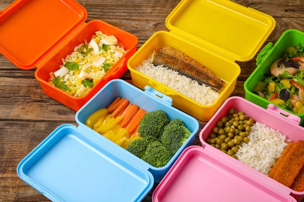 Tahta masada farklı sağlıklı yiyeceklerle dolu birçok plastik kap, yakın plan.