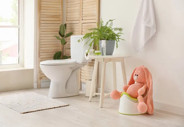 Küçük tuvaletteki beyaz lazımlıkta oturan sevimli oyuncak tavşan.