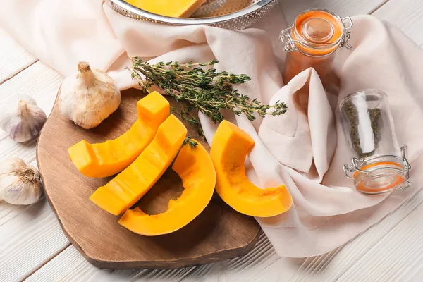 Beyaz ahşap arka planda taze balkabağı parçaları olan tahta.