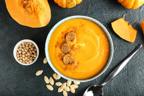 Lezzetli balkabağı kremalı çorba ve koyu arkaplanda tohumlar.