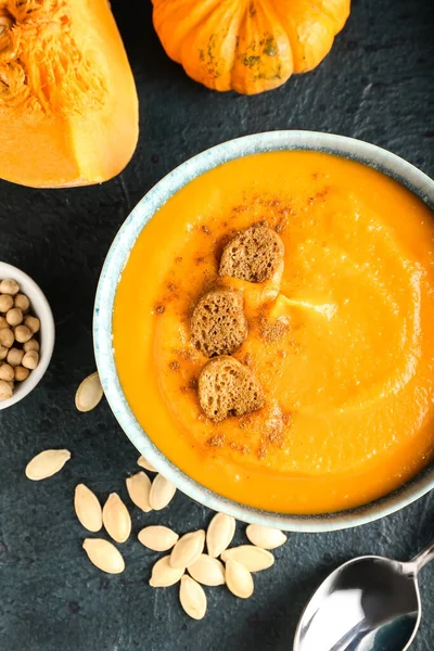 Lezzetli balkabağı kremalı çorba ve koyu arkaplanda tohumlar.