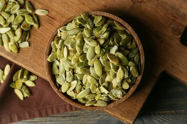 Ahşap zemin üzerinde kabak tohumları olan bir kase