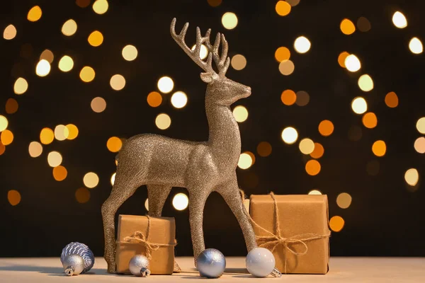 Altın ren geyiği, Noel baloları ve hediye kutuları karanlık arka planda.