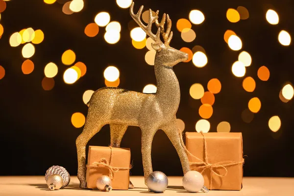 Altın ren geyiği, Noel baloları ve hediye kutuları karanlık arka planda.