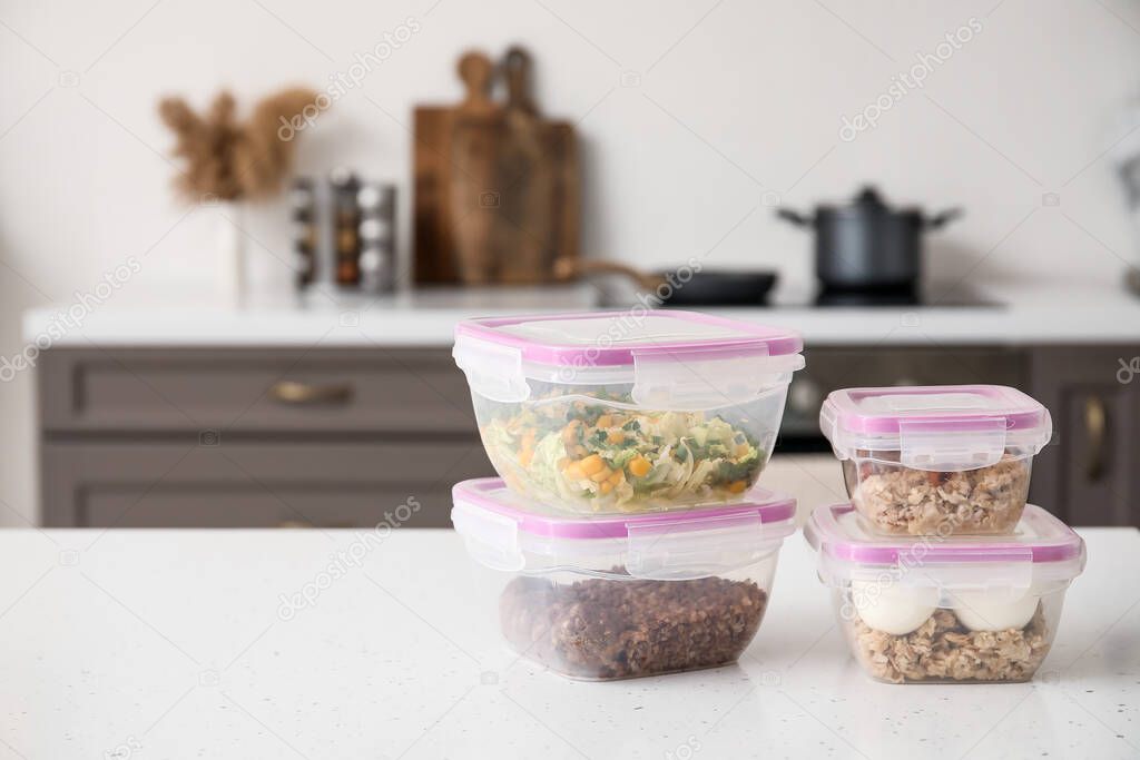 Plastic containers with healthy food on table in kitchen