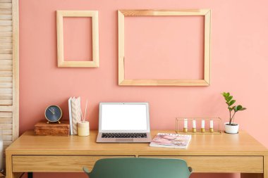 Duvarın yanındaki odada dizüstü bilgisayarı ve çalar saati olan şık bir iş yeri.